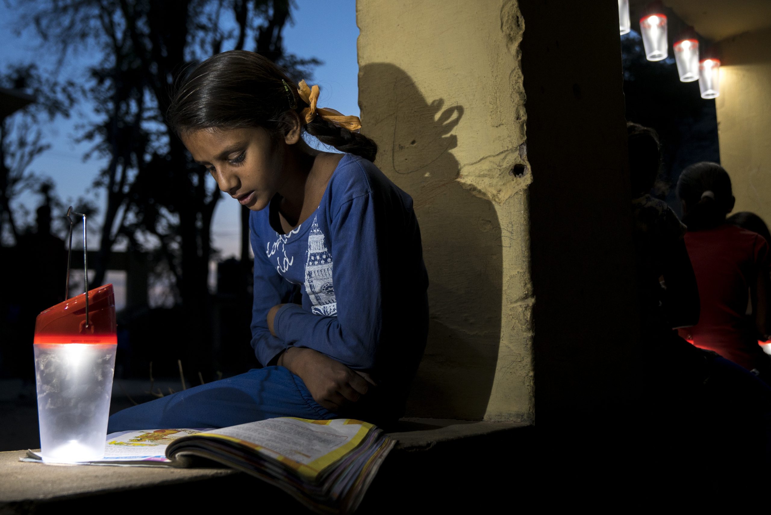 Young Indian girl reading by solar lantern