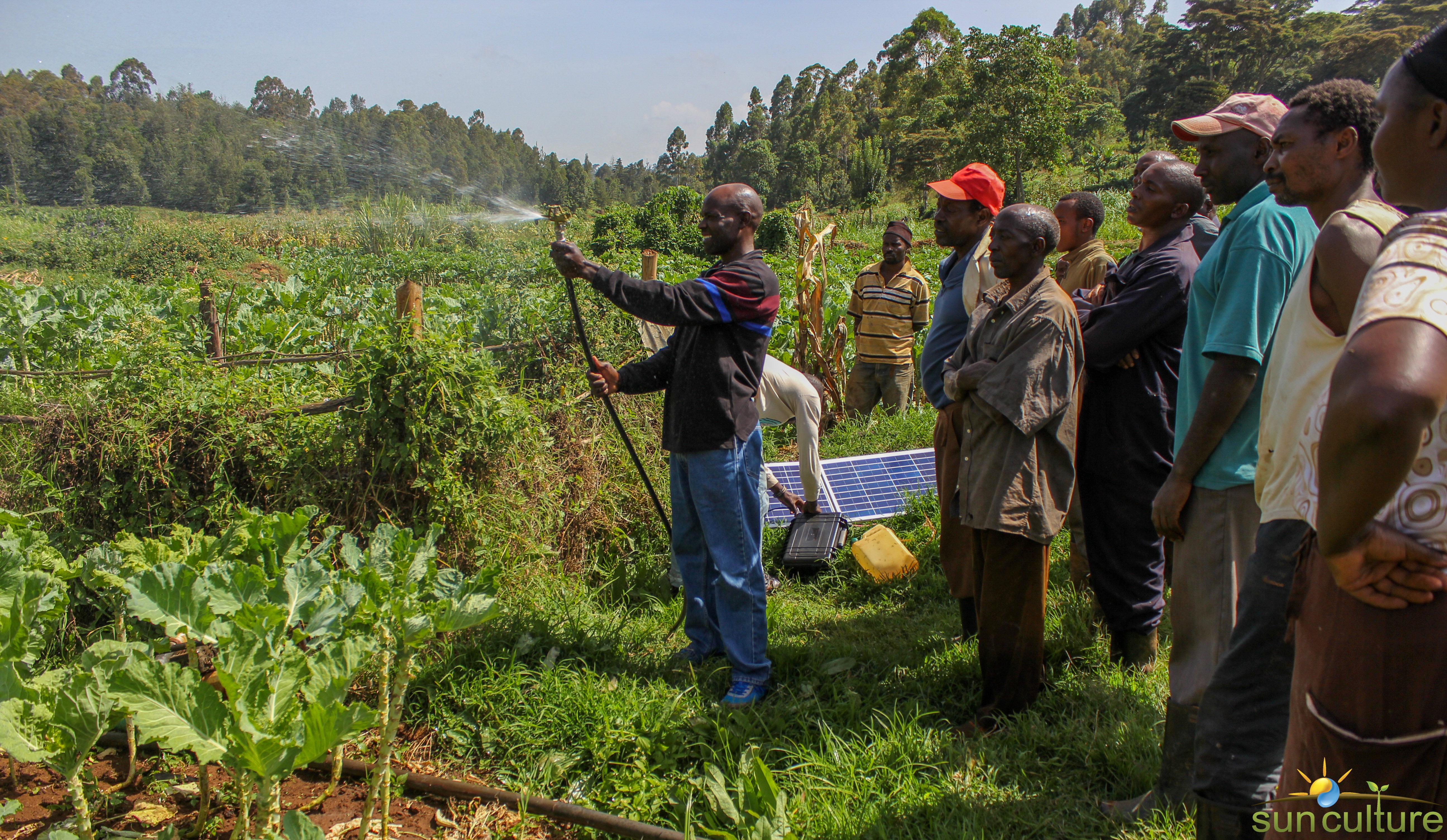 African man showing group a oslar powered irrigation system in the field