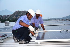 2 en in white hardhats with solar panels n a rof