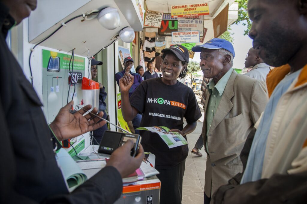 M-KOPA Sales lady describing product to man
