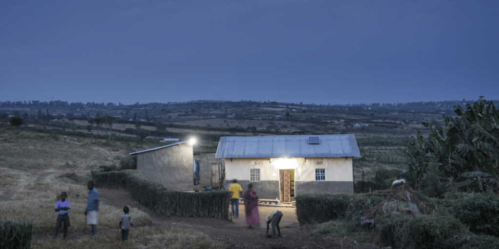 Solar lit house at dusk in village with people