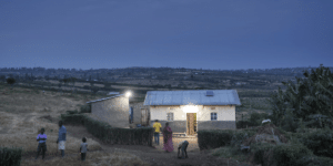 Solar lit house at dusk in village with people