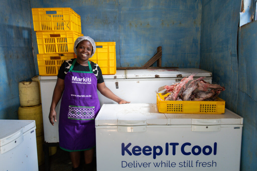 A woman microentrepreneur in Kenya staying by her solar freezers